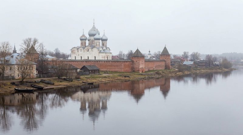 Белокаменный собор с серебряными куполами за кремлёвской стеной у реки