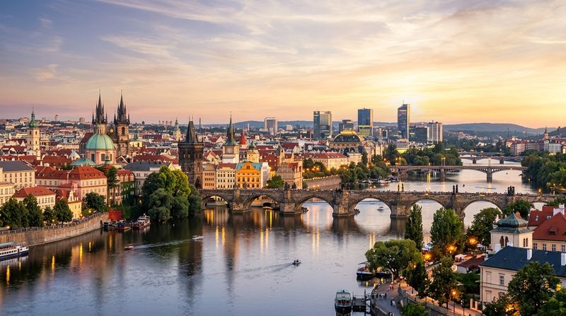 Панорама города на закате: исторические здания, мосты и река